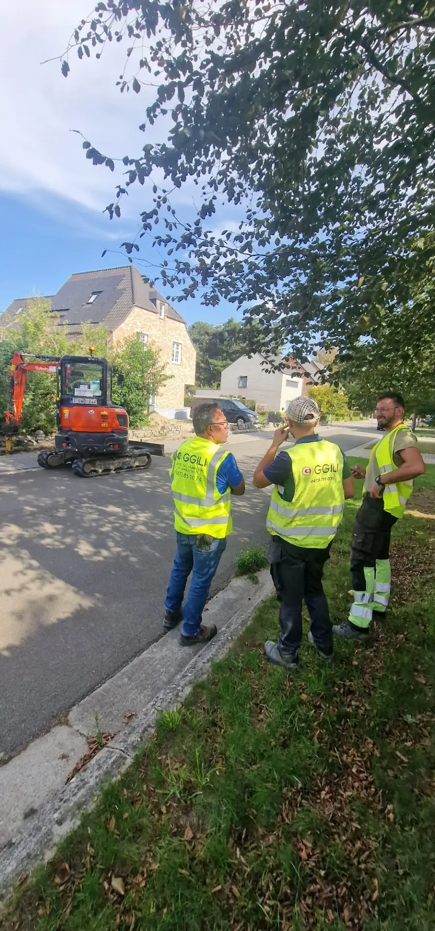 GGILI-werfmedewerkers in fluorescerende hesjes bij nutswerken in een woonwijk